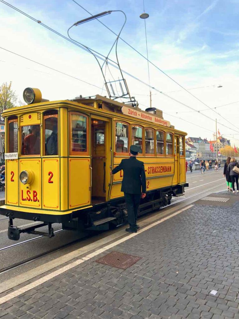 Ένας εισπράκτορας μπροστά στο παλιό κίτρινο τραμ στην Παλιά Πόλη της Ζυρίχης
